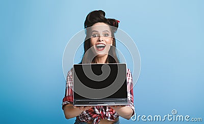 Excited pinup woman in vintage outfit showing laptop with empty screen on blue background, mockup for ad or website Stock Photo