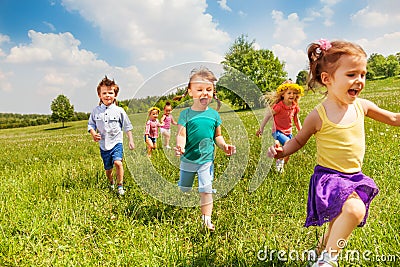 Excited running kids in green field play together Stock Photo