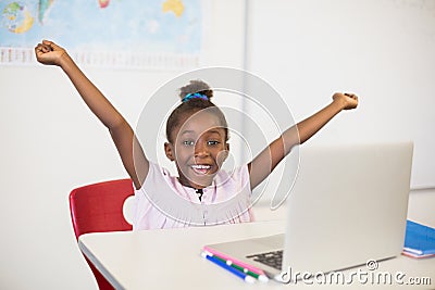 Excited schoolgirl with laptop in classroom Stock Photo