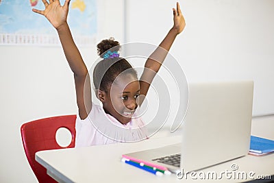 Excited schoolgirl with laptop in classroom Stock Photo