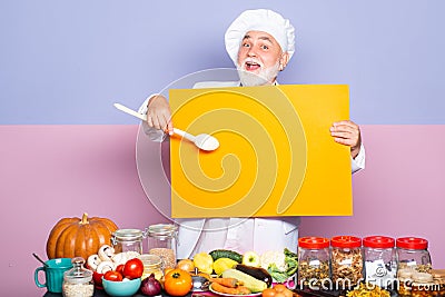 Excited senior chef in cook hat pointing spoon on blank board menu. Funny chef showing blank empty blackboard menu Stock Photo
