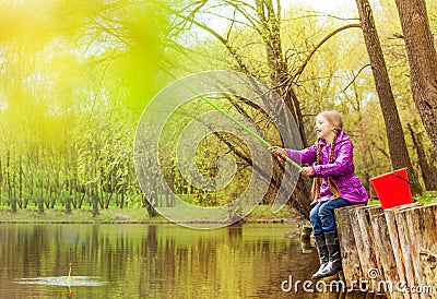 Excited small girl fishing near beautiful pond Stock Photo