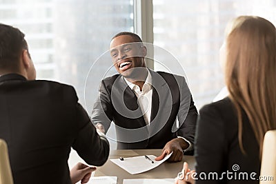 Excited smiling black businessman handshaking white partner at m Stock Photo