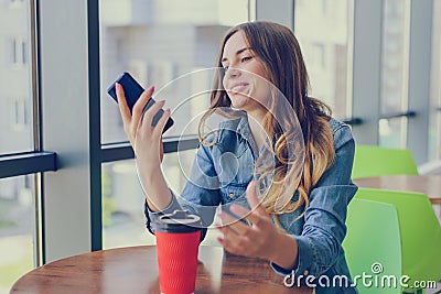 Excited smiling happy woman having a rest in a cafe, she is looking at screen of her smartphone telephone mobile phone sms notific Stock Photo