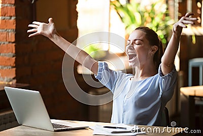 Excited smiling woman celebrating online win, using laptop in cafe Stock Photo