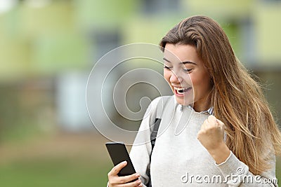 Excited student reading news on a smart phone Stock Photo