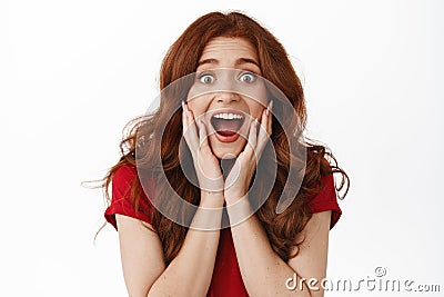 Excited and surprised redhead woman scream from amazement, looking fascinated and impressed, checking out awesome promo Stock Photo