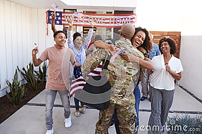 Excited three generation African American family embracing millennial soldier returning home to them Stock Photo