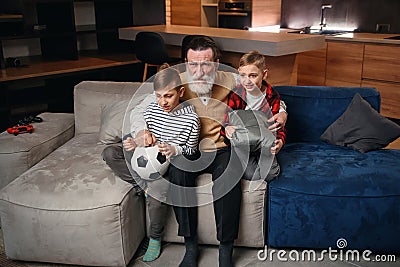 Excited three generations of men sport fans relax in living room celebrate team victory together, overjoyed little boy Stock Photo