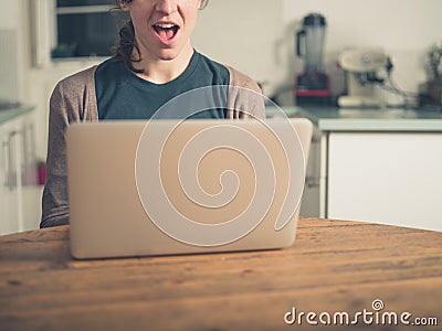 Excited woman with laptop in kitchen Stock Photo