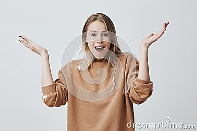 Excited young female with blonde hair exclaiming, looking at camera in amazement with opened mouth, clapping hands, glad Stock Photo