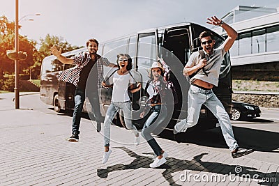 Excited Young People Jumping in front of Tour Bus Stock Photo