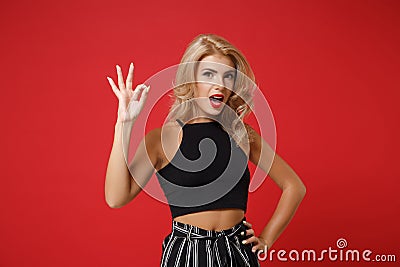 Excited young woman girl in black casual clothes posing isolated on bright red wall background, studio portrait. People Stock Photo