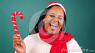 Excited young woman waves candy cane decoration, Christmas hat studio Stock Photo