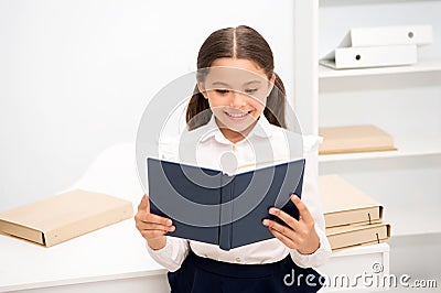 Exciting literature concept. Girl child read book stand white interior. Schoolgirl studying textbook. Kid girl school Stock Photo