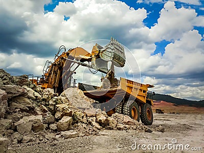 Excuvator is loading a soil on a mining truck in coal mine. Stock Photo