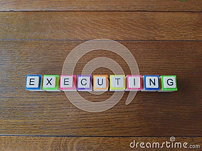 Executing word in colorful letters on wood background Stock Photo