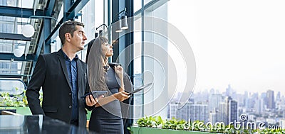 Executive businessman and his secretary is working in modern skyrise office in city downtown looking out the window with Stock Photo