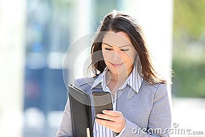 Executive checking smart phone while walks in the street Stock Photo