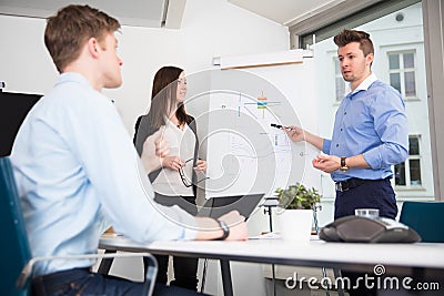 Executive Explaining Presentation To Coworkers In Office Stock Photo