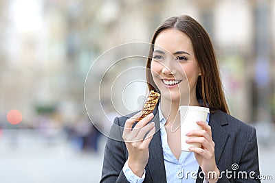 Executive holding snack bar and takeaway coffee in the street Stock Photo