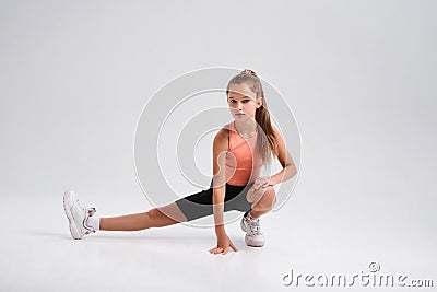 Exercise more. Flexible cute little girl child looking at camera while stretching her body isolated on a white Stock Photo