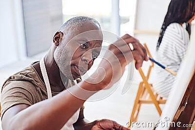 Exercising our creativity gives us an outlet from our daily routines. a middle aged man painting in a art studio. Stock Photo