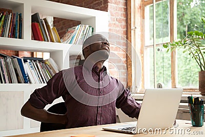 Exhausted african american male office worker having back discom Stock Photo