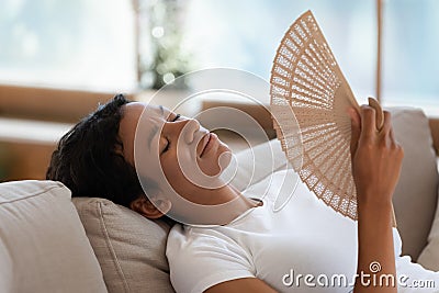 Exhausted biracial woman wave with hand fan suffering from heatstroke Stock Photo