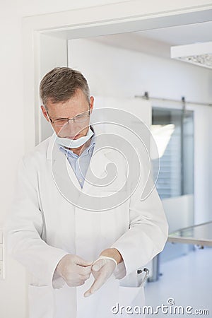 Exhausted doctor leaving a surgery an putting of medical gloves Stock Photo