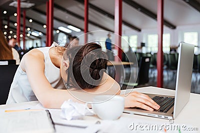 Exhausted fatigued young business woman sleeping on table at workplace Stock Photo