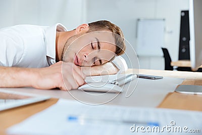 Exhausted fatigued young businessman sleeping on the table Stock Photo