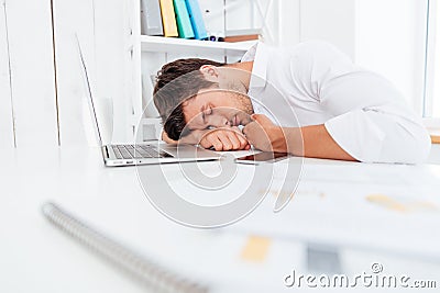 Exhausted fatigued young businessman sleeping on the table Stock Photo