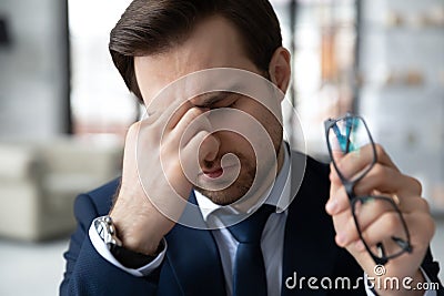 Exhausted male employee suffer from headache at workplace Stock Photo