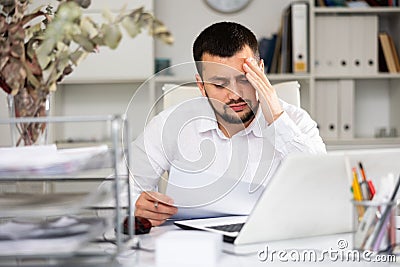 Exhausted male office worker sitting at his desk Stock Photo