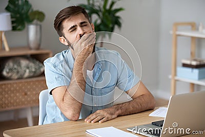Exhausted male worker yawn at workplace feeling unmotivated Stock Photo