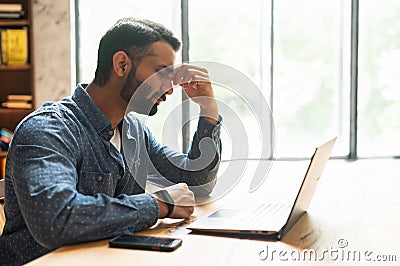 Exhausted middle eastern entrepreneur tired from online work Stock Photo