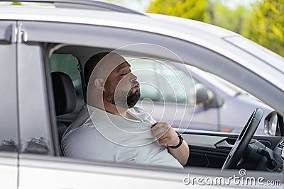 Exhausted overweight man driver feels blood pressure sitting inside car hot weather in traffic jam Stock Photo