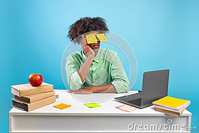 Exhausted student. Black teen guy with painted eyes on stickers sitting at desk and sleeping in front of laptop Stock Photo