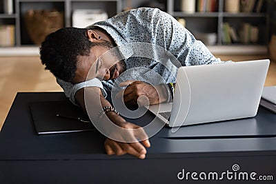 Exhausted tired African American businessman lying on desk and sleeping Stock Photo