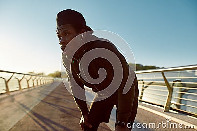 Exhausted, tired african jogger resting after running on the bridge in the morning. Taking a break Stock Photo