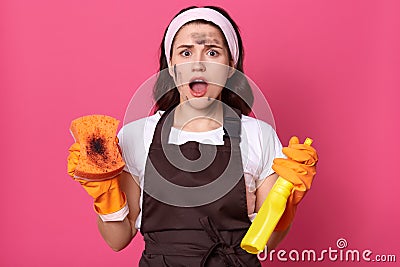 Exhausted tired shocked cute young female with dirty face shouting, opening mouth widely, sick and tired of cleaning up, holding Stock Photo