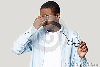 Exhausted unhealthy young african american man rubbing irritated eyes. Stock Photo