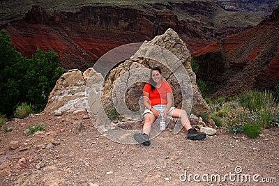 Exhausted woman backpacker resting on the New Hance Trail in the Grand Canyon. Stock Photo