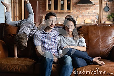Unhappy parents distressed by ill-behaved active son Stock Photo
