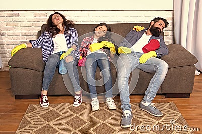 Exhausting cleaning day. Family mom dad and daughter with cleaning supplies sit on couch. Family care about cleanliness Stock Photo