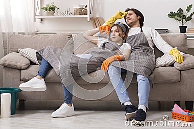 Exhausting Household Chores. Tired couple sitting on couch after cleaning apartment Stock Photo