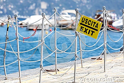 Exit into a corridor in a pier of an Italian port by the sea. No tourists due to the pandemic-induced crisis. Sign. Stock Photo