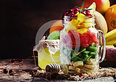 Exotic fruit salad with banana, kiwi, grapefruit, mango, cranberry and lemon juice and honey, served in a glass jar. Vintage wood Stock Photo