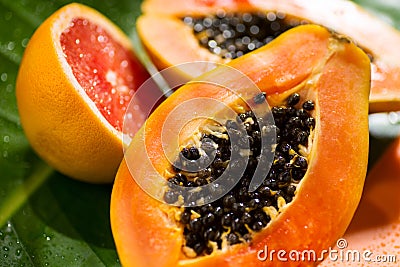Exotic fruits background. Papaya and orange citrus fresh fruits on tropical leaf green background Stock Photo